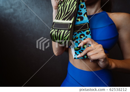 Beautiful girl with a sports figure stands on a dark background and pose for the camera. 62538212