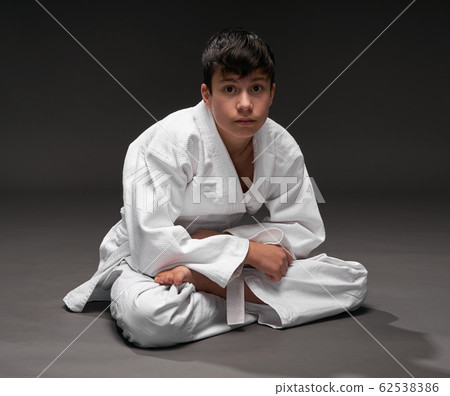 a teenager dressed in martial arts clothing poses 62538386