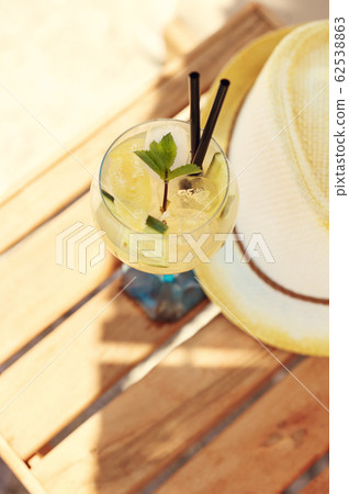 Cucumber drink cocktail, straw hat on wooden table 62538863