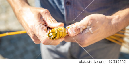 a man knitting his Easter whip from a rod a man knitting his Easter whip from a rod 62539332