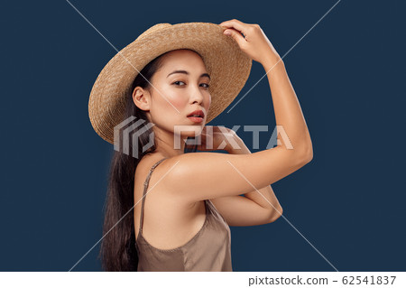 Freestyle. Young woman in hat standing isolated on dark blue posing sensual 62541837