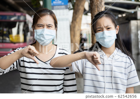 Asian child girl,woman show thumbs down,wearing medical face mask in public area,risk of disease,bad air pollution,hard to breathe,epidemic,spread of Coronavirus,2019 covid-19,Wuhan,flu season Asian child girl,woman show thumbs down,wearing medical face mask in public area,risk of disease,bad air pollution,hard to breathe,epidemic,spread of Coronavirus,2019 covid-19,Wuhan,flu season 62542656