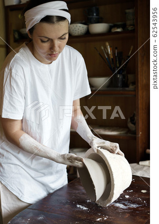 Female hands hold a bowl for casting clay products.  62543956