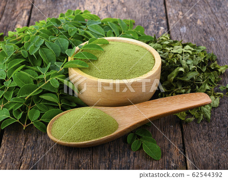 Moringa powder in wooden bowl with fresh Moringa Moringa powder in wooden bowl with fresh Moringa 62544392