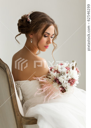 Close up portrait of young bride in a beautiful dress holding a bouquet of flowers in bright white studio. Wedding concept. Close up portrait of young bride in a beautiful dress holding a bouquet of flowers in bright white studio. Wedding concept. 62546299