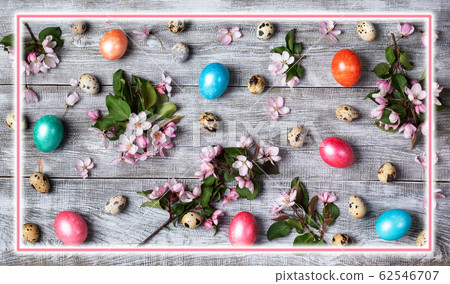 Easter festive layout of pink Apple tree twigs, quail and colored hen eggs on wooden table with rectangular pink glowing frame above. Easter decorations composition. Top view, flat lay. Easter festive layout of pink Apple tree twigs, quail and colored hen eggs on wooden table with rectangular pink glowing frame above. Easter decorations composition. Top view, flat lay. 62546707