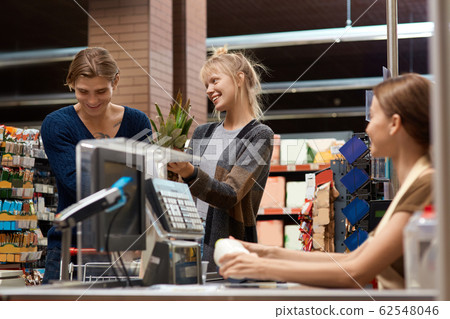 Daily Shopping. Couple at the supermarket standing at cashier checkout counter laughing cheerful 62548046