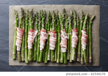 Raw green asparagus wrapped with bacon 62548170