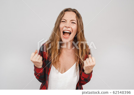 Freestyle. Young woman with freckles standing isolated on grey hands in fists screaming to camera motivated Freestyle. Young woman with freckles standing isolated on grey hands in fists screaming to camera motivated 62548396