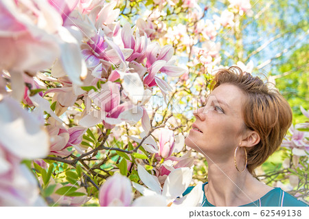 Portrait of young woman near blooming magnolia 62549138