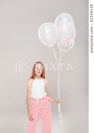 Inclusive Beauty. Girl with freckles standing isolated on grey holding balloons posing smiling excited 62549139