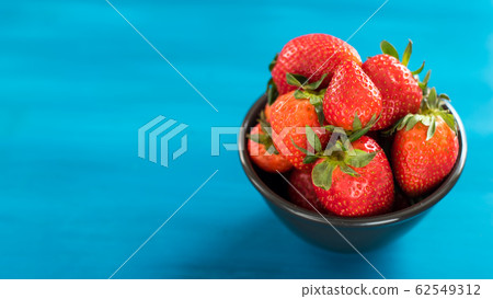 bowl of fresh strawberries on a wooden table 62549312