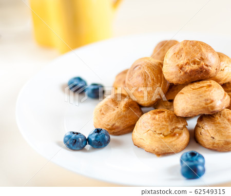 profiteroles with Blueberries on a white plate profiteroles with Blueberries on a white plate 62549315
