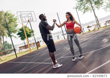 Outdoors Activity. African couple standing on basketball court giving high five shaking hands cheerful 62549671