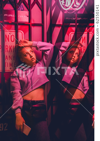 Nihgtlife. Teen girl leaning back isolated on club wall mirror reflection looking up pensive 62550141