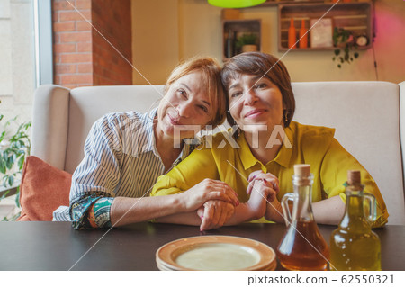 Attractive mature mother and daughter eating  62550321
