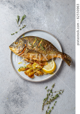 Grilled sea bream or dorada on gray plate. Gray background 62550963