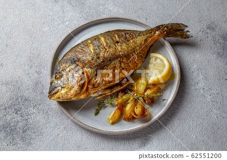 Grilled sea bream or dorada on gray plate. Gray background Grilled sea bream or dorada on gray plate. Gray background 62551200