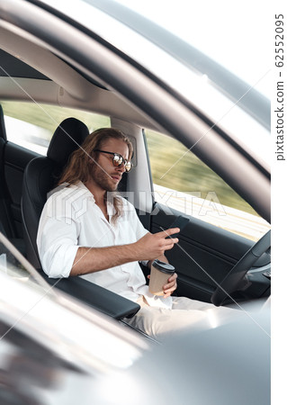 Young adult man using smartphone, sitting in car 62552095