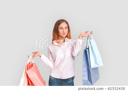 Shopping Concept. Young woman standing isolated on white with bags looking aside pensive Shopping Concept. Young woman standing isolated on white with bags looking aside pensive 62552438