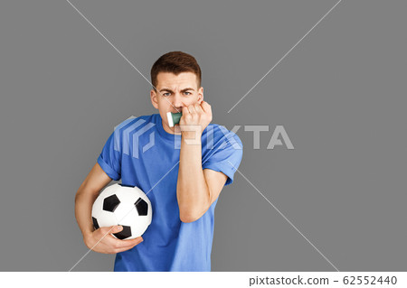 Freestyle. Young man standing isolated on grey with football ball making noise motivated Freestyle. Young man standing isolated on grey with football ball making noise motivated 62552440