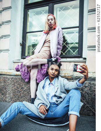Two teenage girls infront of university building smiling, having fun, lifestyle real people concept Two teenage girls infront of university building smiling, having fun, lifestyle real people concept 62552717