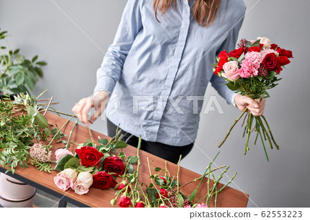 Floral shop concept . Florist woman creates flower arrangement. Beautiful bouquet of mixed flowers. Handsome fresh bunch. Flowers delivery 62553223