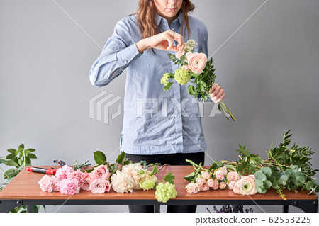 Woman florist creating beautiful bouquet in flower shop. Work in flower shop. Flowers delivery. 62553225