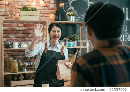 woman seller giving paper bag to male customer woman seller giving paper bag to male customer 62557062