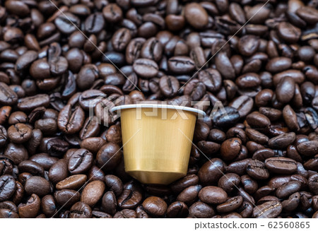 Golden coffee capsule on the dark roasted coffee 62560865
