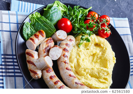 French potato aligot on a black plate with sausage 62561580