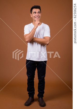 Young handsome Hispanic man against brown background Young handsome Hispanic man against brown background 62566254