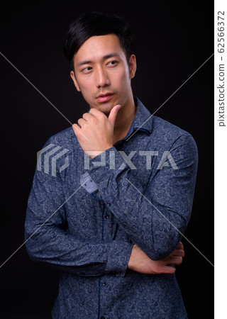Young handsome Asian businessman against black background 62566372