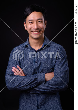 Young handsome Asian businessman against black background 62566373