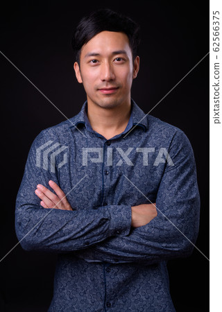 Young handsome Asian businessman against black background 62566375