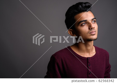 Young Indian man against gray background Young Indian man against gray background 62568342