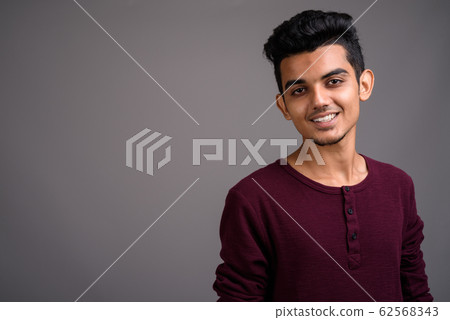 Young Indian man against gray background Young Indian man against gray background 62568343