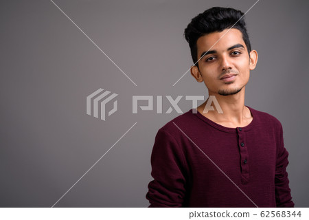 Young Indian man against gray background 62568344