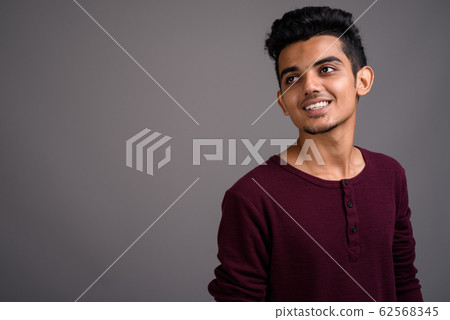 Young Indian man against gray background Young Indian man against gray background 62568345