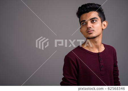 Young Indian man against gray background Young Indian man against gray background 62568346