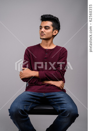 Young Indian man against gray background 62568355