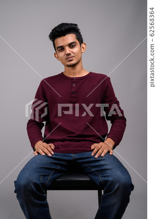 Young Indian man against gray background 62568364
