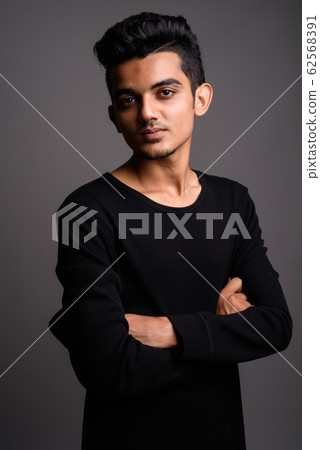 Young Indian man against gray background Young Indian man against gray background 62568391