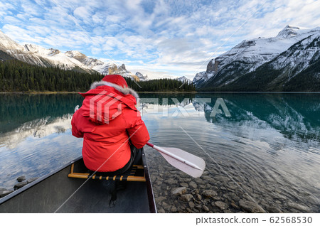 Man traveler holding paddle on red canoe in Spirit Man traveler holding paddle on red canoe in Spirit 62568530
