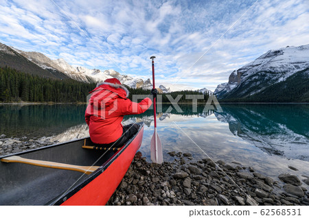 Man traveler holding paddle on red canoe in Spirit Man traveler holding paddle on red canoe in Spirit 62568531