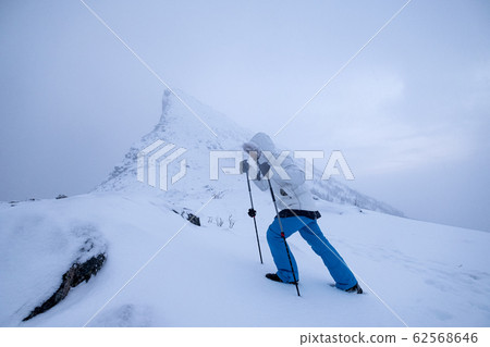 Man climber with trekking poles standing on snow 62568646