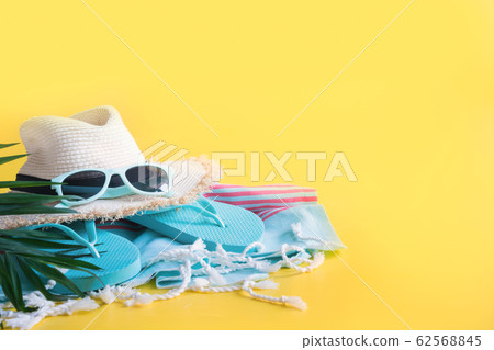 Beach straw sun hat, towel on yellow. Summer Beach straw sun hat, towel on yellow. Summer 62568845