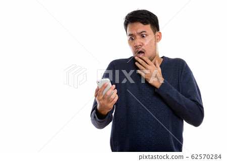 Studio shot of young Asian man holding mobile phone looking scar 62570284