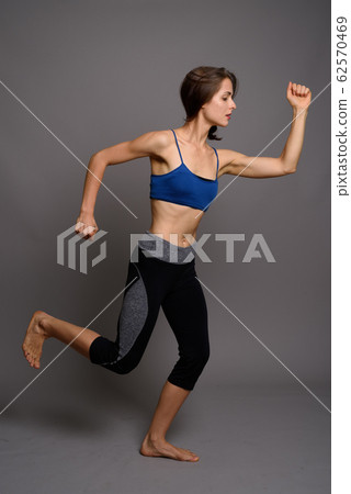 Young beautiful woman ready for gym against gray background Young beautiful woman ready for gym against gray background 62570469