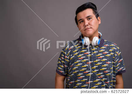 Young multi-ethnic man wearing headphones against gray backgroun 62572027